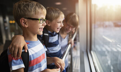 Kinder im Alter von 7 und 11 Jahren beobachten Flugzeuge durch die Fenster der Lobby und haben Spaß