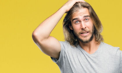  Junger Mann mit langen Haaren zeigt Emotionen und ist wütend und frustriert