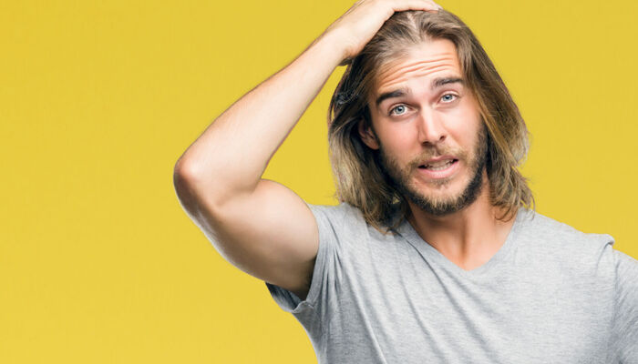  Junger Mann mit langen Haaren zeigt Emotionen und ist wütend und frustriert
