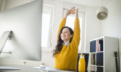 Frau dehnt sich am Arbeitsplatz im mobile Office