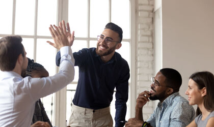 Begeisterte Geschäftsleute der Millennial-Generation geben ihren  Kollegen bei einem Meeting ein High Five