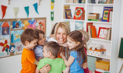 Kinder im Kindergarten umarmen ihre Erzieherin.