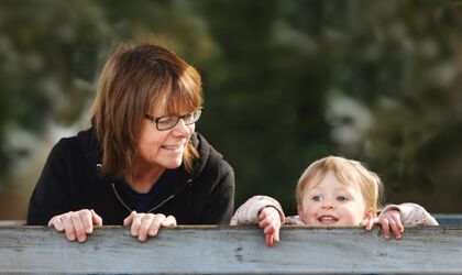 Freches 2-jähriges Mädchen, das mit ihrer Großmutter über ein Klettergerüst in einem Spielpark späht