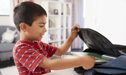 Junge packt Rucksack für die Schule
