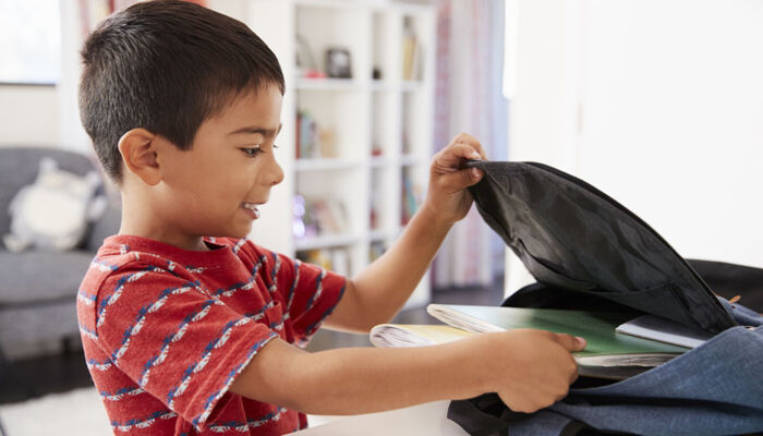 Junge packt Rucksack für die Schule