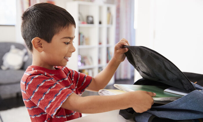 Junge packt Rucksack für die Schule