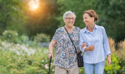 Seniorin und Betreuerin zu Fuß im Freien bei Sonnenuntergang