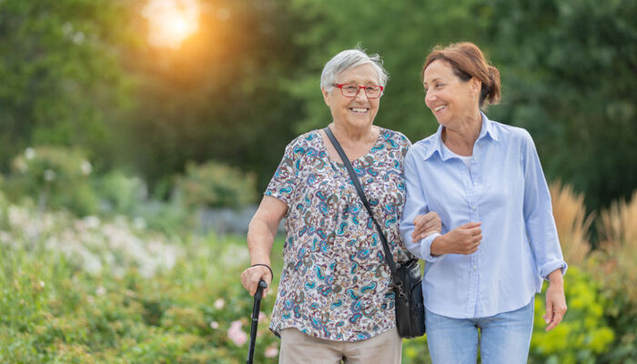 Seniorin und Betreuerin zu Fuß im Freien bei Sonnenuntergang