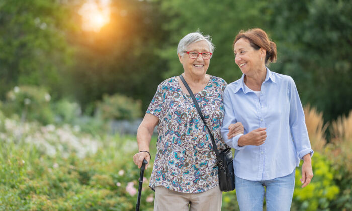 Seniorin und Betreuerin zu Fuß im Freien bei Sonnenuntergang