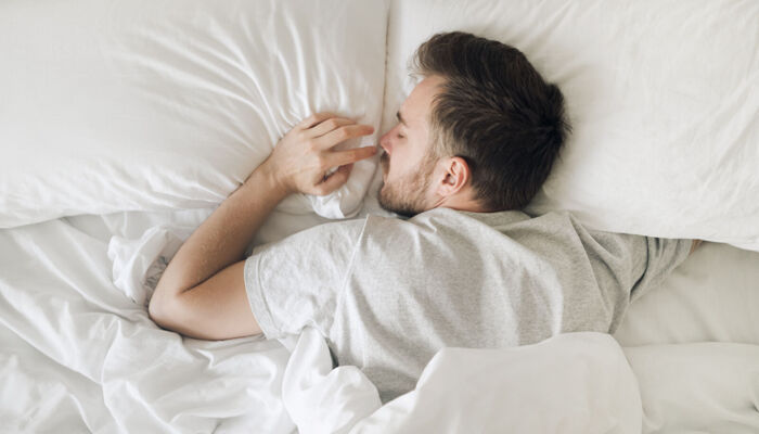 Schlafender Mann in weißem Bett