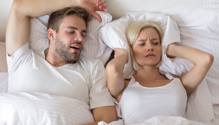 Schnarchender Mann und schlaflose Frau im Bett