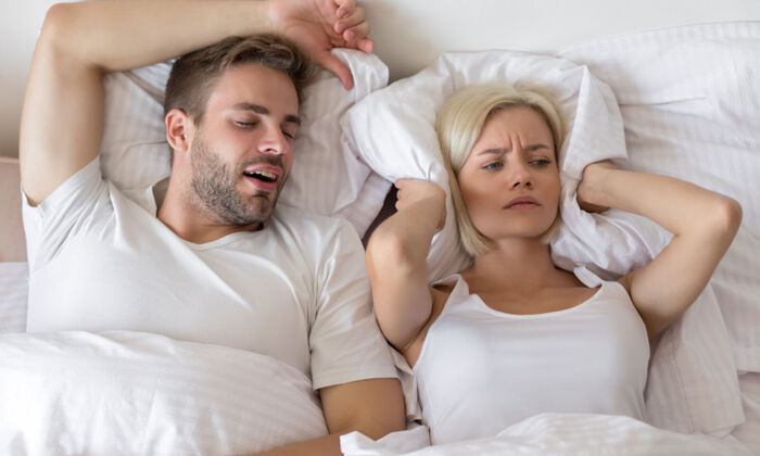 Schnarchender Mann und schlaflose Frau im Bett