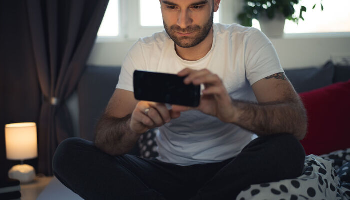 junger Mann im Bett mit Smartphone
