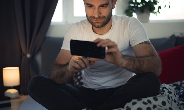 junger Mann im Bett mit Smartphone