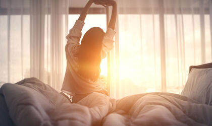 Frau streckt sich im Bett nach dem Aufwachen