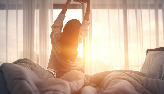 Frau streckt sich im Bett nach dem Aufwachen
