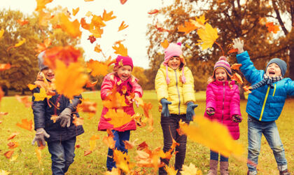fröhliche Kinder spielen im Park mit Herbstlaub