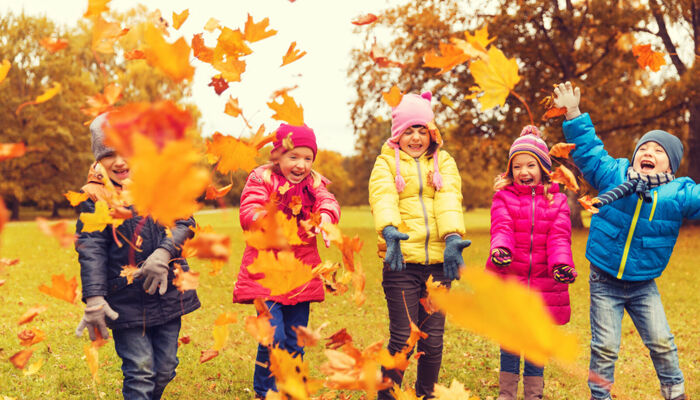 fröhliche Kinder spielen im Park mit Herbstlaub