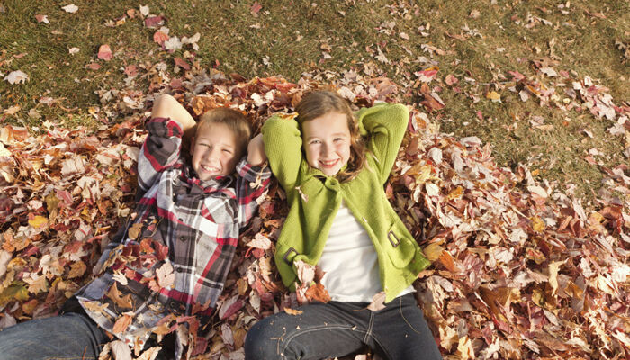 ein Junge und ein Mädchen liegen entspannt im herbstlaub