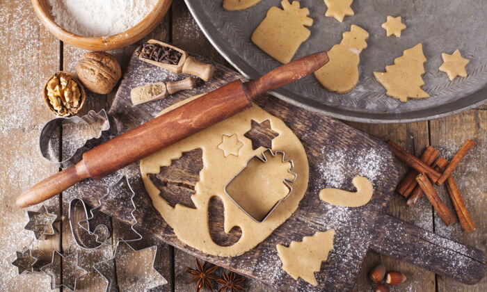 Weihnachtsbäckerei mit Nudelholz, Teig und Ausstechern auf einem Holztisch