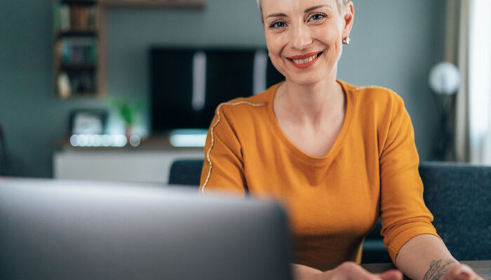 Moderne Frau, die zu Hause arbeitet. Geschäftsfrau mit Laptop und Dokumenten, Kaffee trinken. Konzentriert aussehen