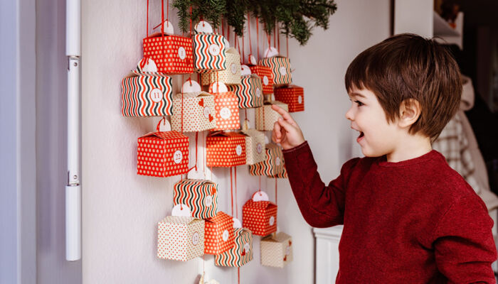 ein kleiner Junge zeigt auf einen handgemachten Adventskalender an der Wand