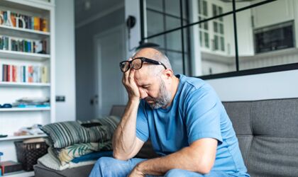 Ein älterer Mann mit Depressionen sitzt zu Hause auf dem Sofa