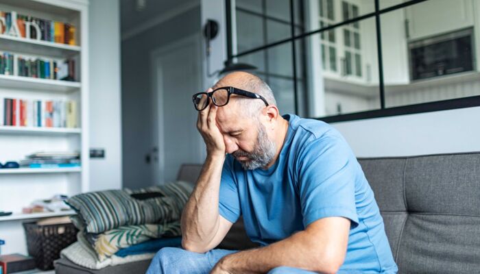 Ein älterer Mann mit Depressionen sitzt zu Hause auf dem Sofa