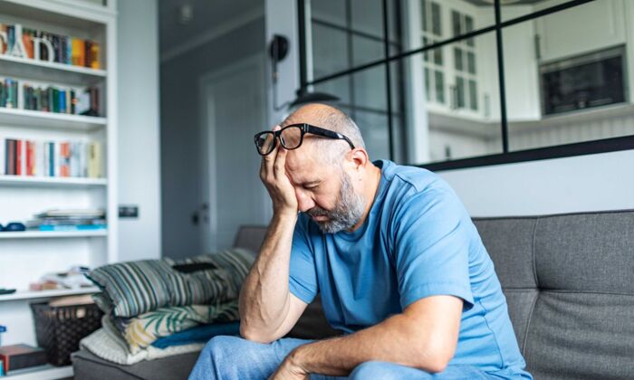 Ein älterer Mann mit Depressionen sitzt zu Hause auf dem Sofa