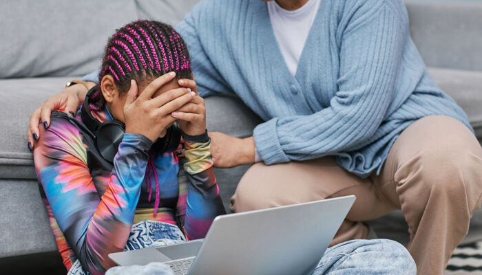 Porträt eines depressiven Mädchens, das auf dem Boden weint, während seine Mutter es tröstet