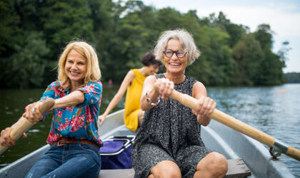  Lächelnde Frau und Freundinnen rudern auf dem See