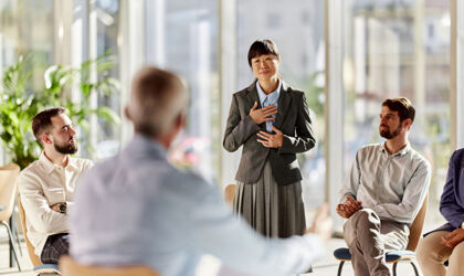 Belastete weibliche asiatische Business Unternehmerin spricht in Gruppen Therapie Sitzung im Büro.
