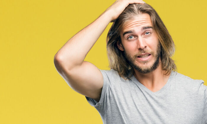  Junger Mann mit langen Haaren zeigt Emotionen und ist wütend und frustriert