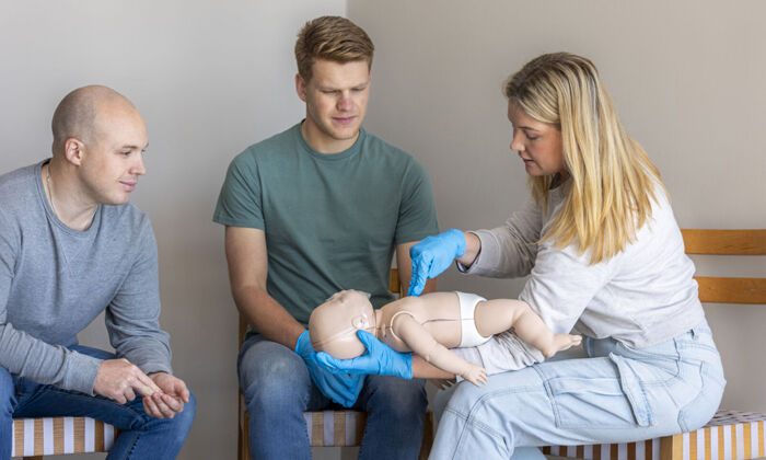 Erste-Hilfe-Ausbilderin demonstriert die richtige Methode für die Herzdruckmassage bei einer Säuglingspuppe
