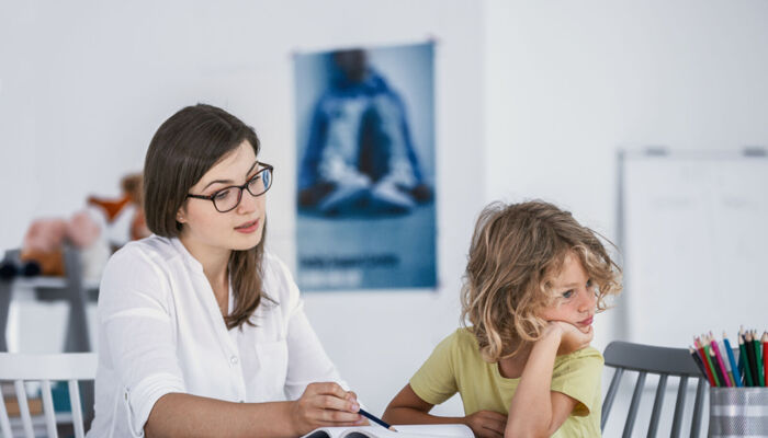 Ein gelangweilter unkonzentrierter Junge mit seiner Mutter während der Hausaufgaben
