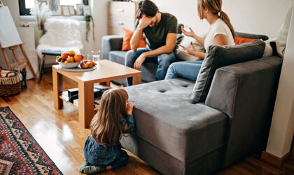 Eltern mit Beziehungsproblemen streiten auf dem Sofa vor ihrem kleinen Kind