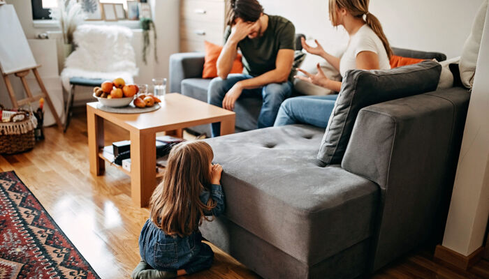 Eltern mit Beziehungsproblemen streiten auf dem Sofa vor ihrem kleinen Kind