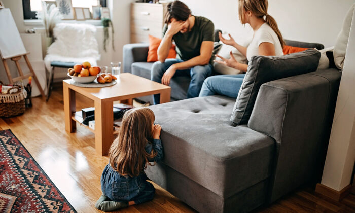 Eltern mit Beziehungsproblemen streiten auf dem Sofa vor ihrem kleinen Kind