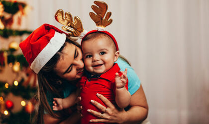 Mutter und Baby in weihnachtlichen Kostümen lachen 