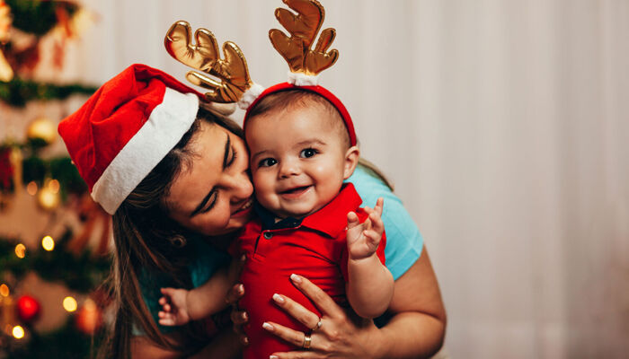 Mutter und Baby in weihnachtlichen Kostümen lachen 