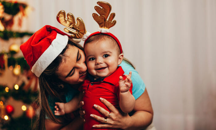 Mutter und Baby in weihnachtlichen Kostümen lachen 