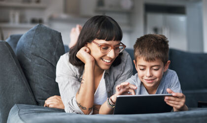 Mutter und kleiner Sohn, die zu Hause auf dem Sofa gemeinsam ein Tablet benutzen