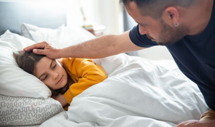 Vater, der sich um die Gesundheit seiner Tochter sorgt, an Ihrem Bett sitzend
