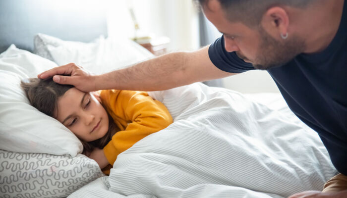 Vater, der sich um die Gesundheit seiner Tochter sorgt, an Ihrem Bett sitzend