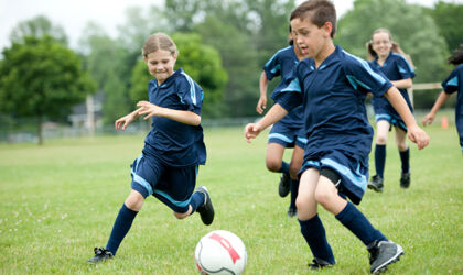 Jungen und Mädchen spielen Fußball auf Rasen