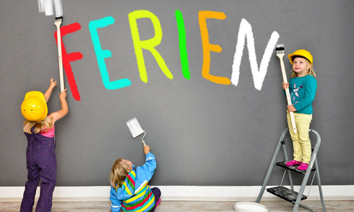 Drei Kinder, die gemeinsam  Wände streichenm und das Wort Ferien malen