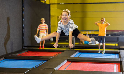 Tween Mädchen macht Split im Sprung in der Indoor-Trampolin-Arena